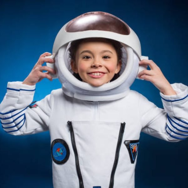 Little girl in space suit wearing helmet  and smiling at camera